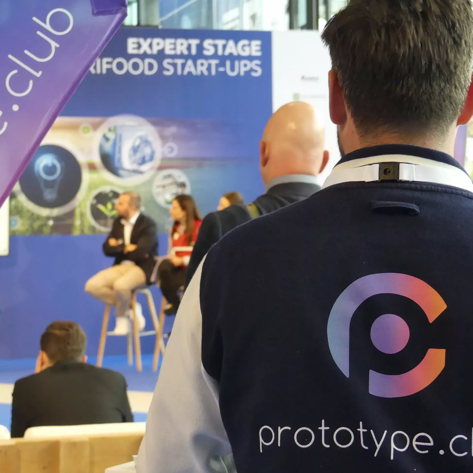 Christian Schweizer rechts im Vordergrund. Man sieht seinen Rücken mit dem prototype.club Logo auf der Jacken-Rückseite.