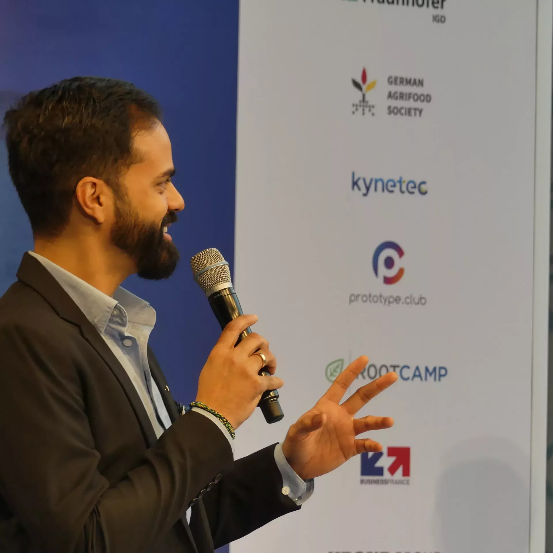 Christopher Armstrong, DLG, mit Mikrophon in Nahaufnahme auf der Bühne des Messestandes.